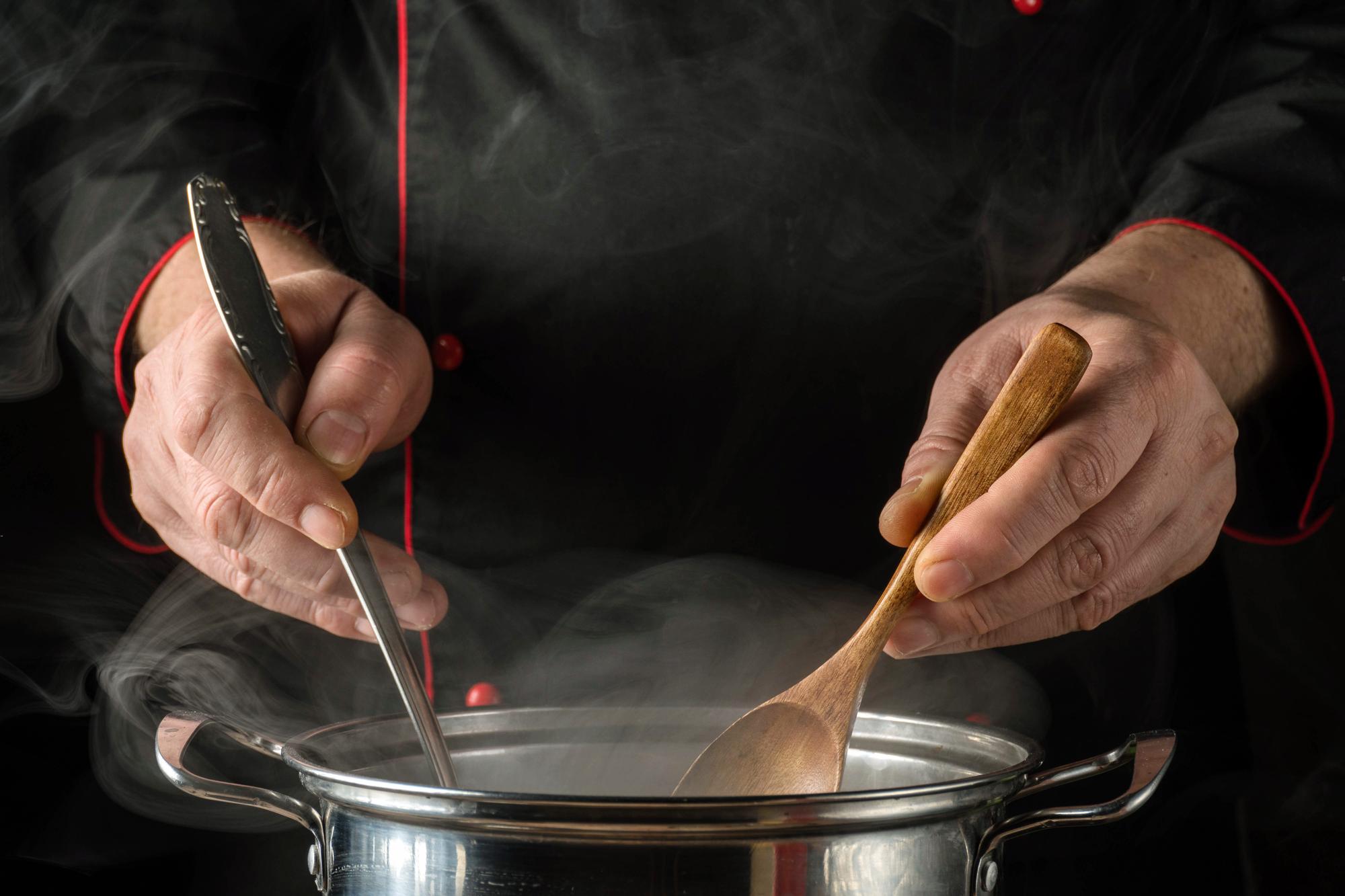 Cook tasting sauce in a copper pan